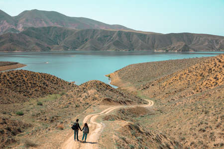 young woman and man hand in hand near lake