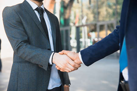 Handshake of two young businessmen in classic suitsの写真素材