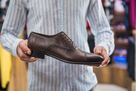 man holding brown shoes in shop