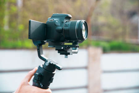 Man hand holding a gimbal stabilizer outdoor.