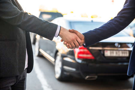 business man shaking hands with client in car dealershipの写真素材