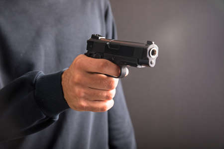 Killer with gun close-up on dark background