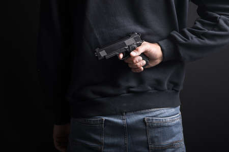 young man hand gun in back