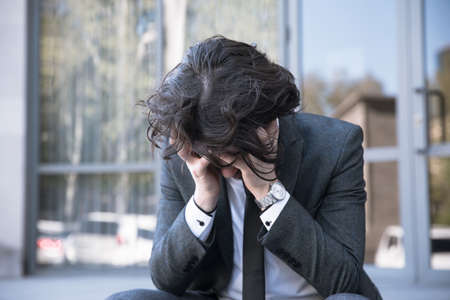 Businessman in depression sitting in street. Problems with Businessの写真素材