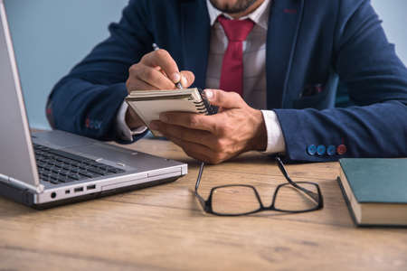 man working in notepad and computer in officeの写真素材