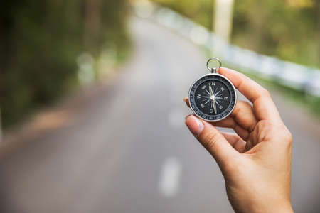 woman hand holding compass in road backgroundの写真素材