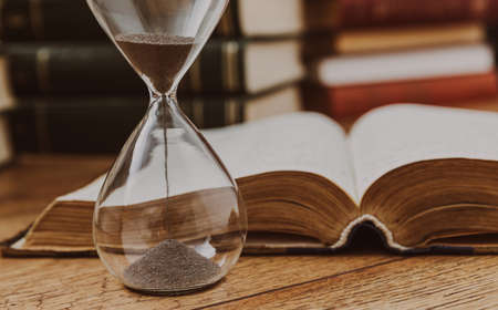 hourglass with book on the wooden background