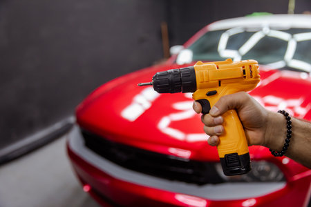 Car repair holding drill while working on engineの写真素材