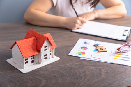 real estate concept, woman hand house key and house model on tableの写真素材