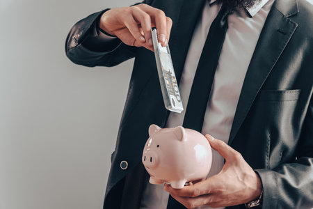 A businessman saves dollar bills in a piggy bank. Savings for a rainy dayの写真素材