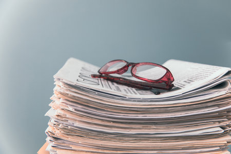 Glasses on newspapers on a gray backgroundの写真素材