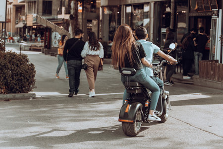 A man rides with a girl around the city on a scooterの写真素材