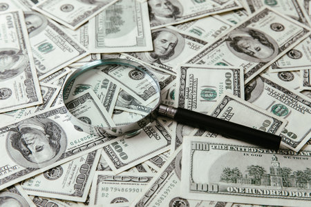 Dollar bills and a magnifying glass on the tableの写真素材