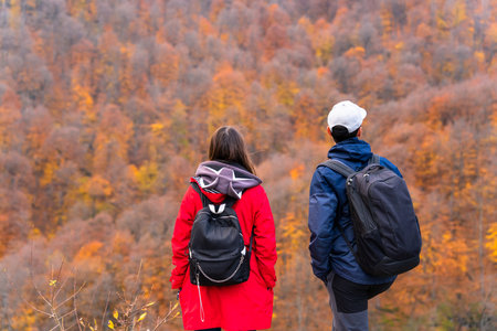 A young couple is standing with backpacks. Against the backdrop of an autumn forestの写真素材
