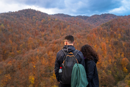 A young couple is standing with backpacks. Against the backdrop of an autumn forestの写真素材