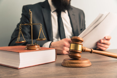The judge examines the papers while sitting in front of the hammer and scales. scales of justiceの写真素材