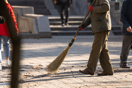 Janitor sweeping dirt on the street during the dayの写真素材