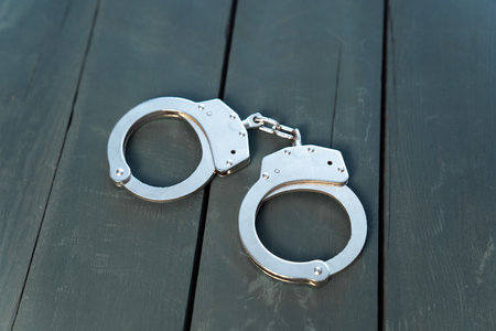 Metal handcuffs on a wooden tableの写真素材