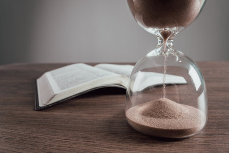Hourglass and open book on the tableの写真素材
