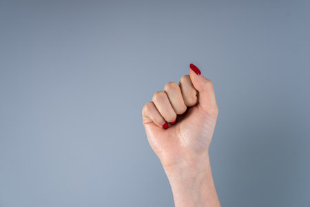 Raised up female fist on a gray backgroundの写真素材
