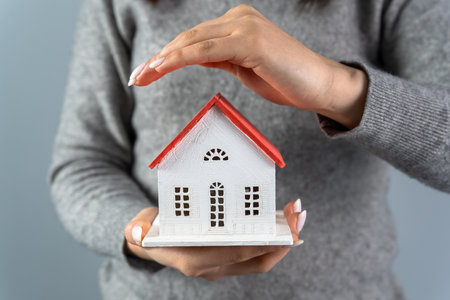 Woman holding and protecting house mockup with her handの写真素材