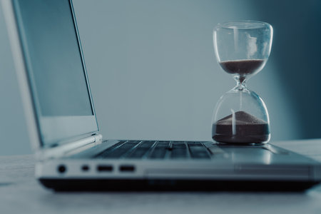 Laptop and hourglass on the table