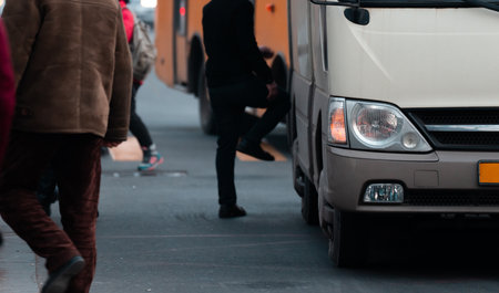 People get into public transport at a bus stopの写真素材