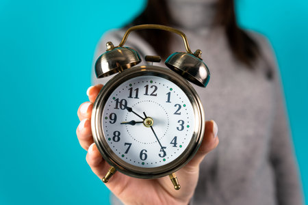 Woman holding an alarm clock in her hand on a blue background