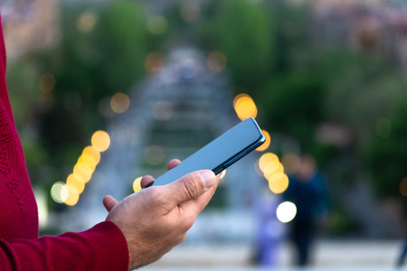 Against the backdrop of the city, a man holds a phone in his handの写真素材
