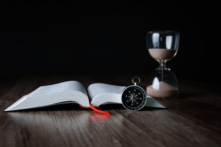 On the table is a book, a compass and an hourglass