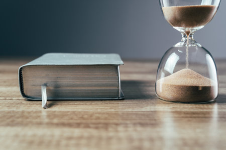 Hourglass and book on the tableの写真素材