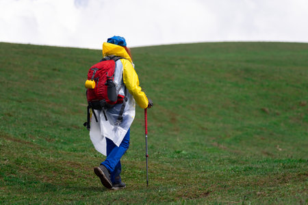 Woman traveler with a backpack goes uphill during the day