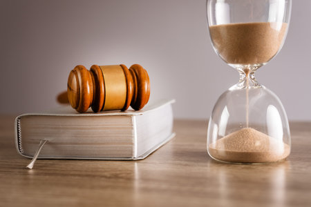 Judge's gavel, hourglass and book on the tableの写真素材