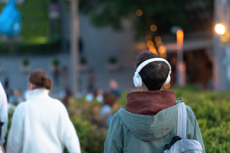 The guy walks around the city in headphones in the evening