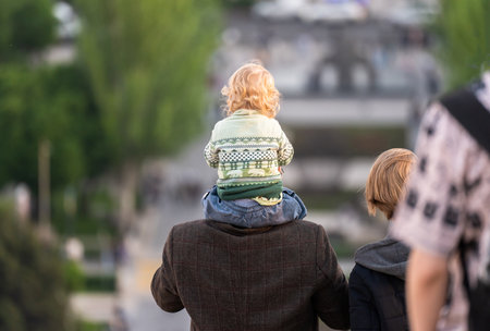 Boy sitting on his father's back in the cityの写真素材