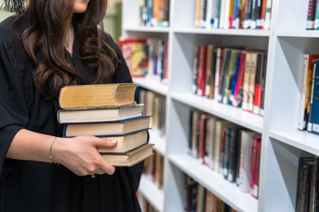 Woman holding a pile of books in the libraryの写真素材