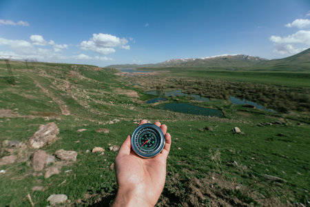 Against the background of the field holds a compass under the open skyの写真素材