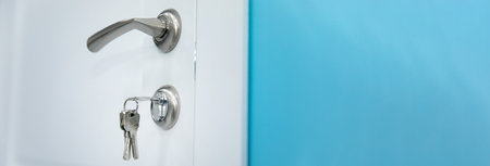 Key in a keyhole at the white door. House door with metal keys.の写真素材