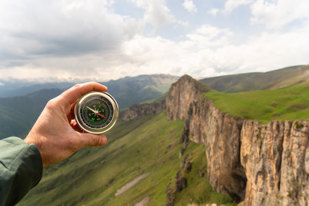 On the ground a compass with a view of the mountain during the day