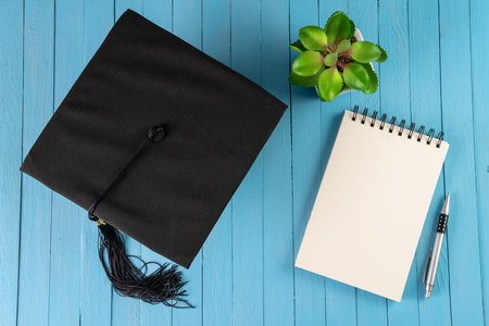 Student hat and notepad on blue wooden tableの写真素材
