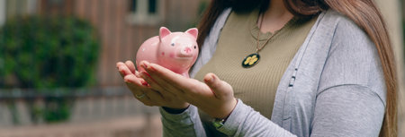 Young woman with piggy bank in streetの写真素材