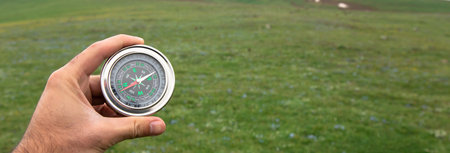 man holding compass on green landscape background