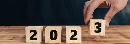 A person's hand puts a wooden cube for the year 2023の写真素材