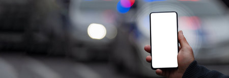Holding a phone against the backdrop of police cars in the cityの写真素材