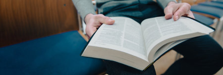 Man reading a book while sitting on a chairの写真素材