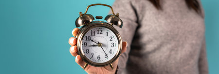 Woman holding an alarm clock in her hand on a blue background