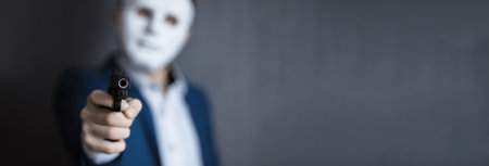 man face mask with hand gun on dark backgroundの写真素材