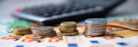 coins on money with calculator on deskの写真素材