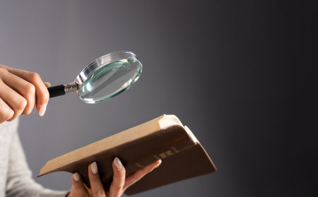 Young woman looking at a book with a magnifying glassの写真素材