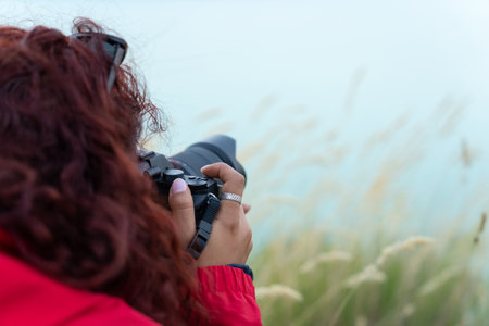 Woman holding a camera by the lake in the eveningの写真素材